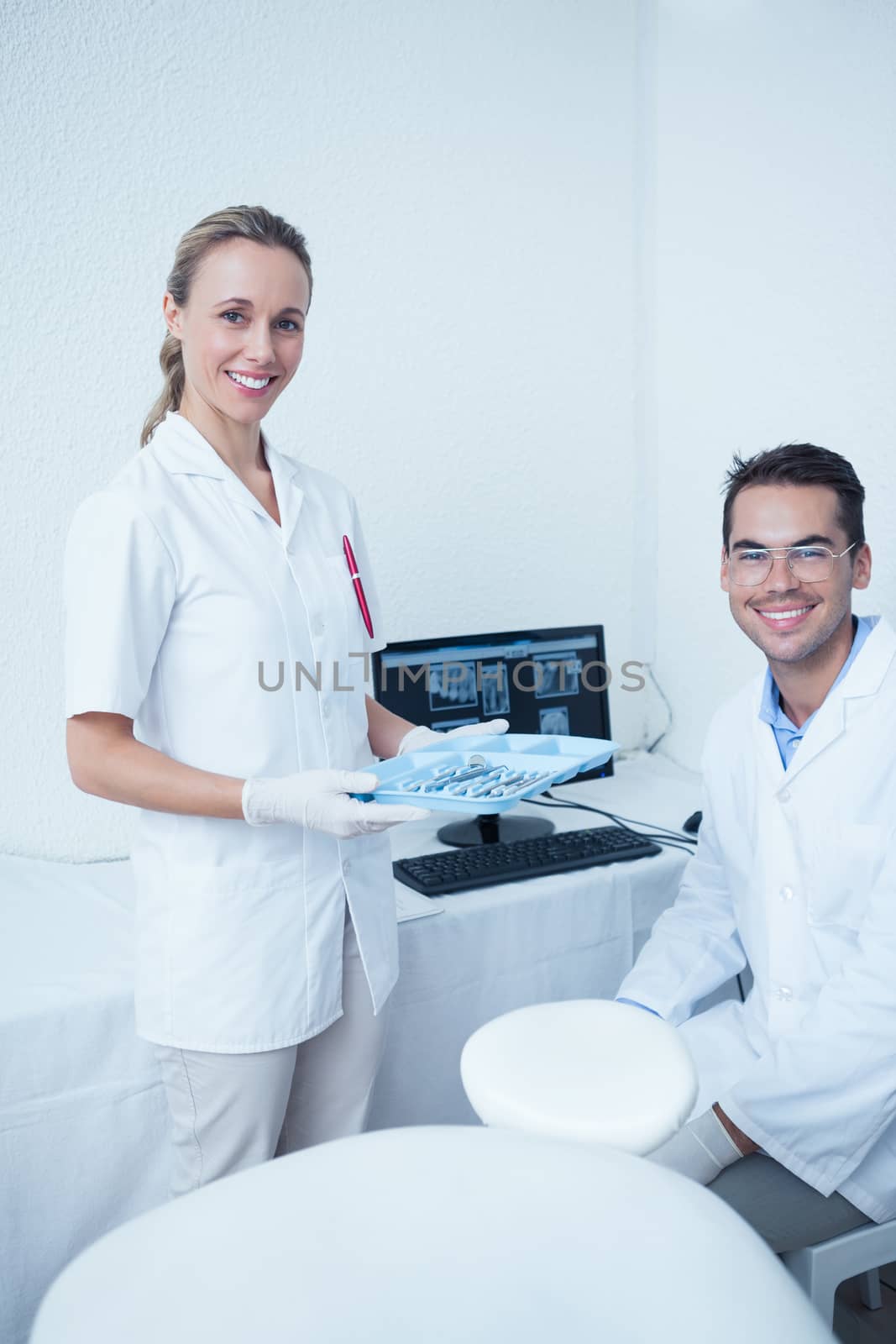 Portrait of smiling male and female dentists with computer monitor