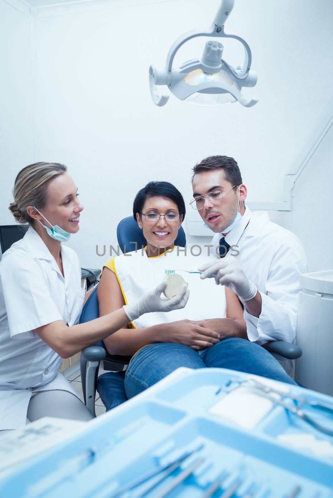 Dentists showing woman prosthesis teeth by Wavebreakmedia
