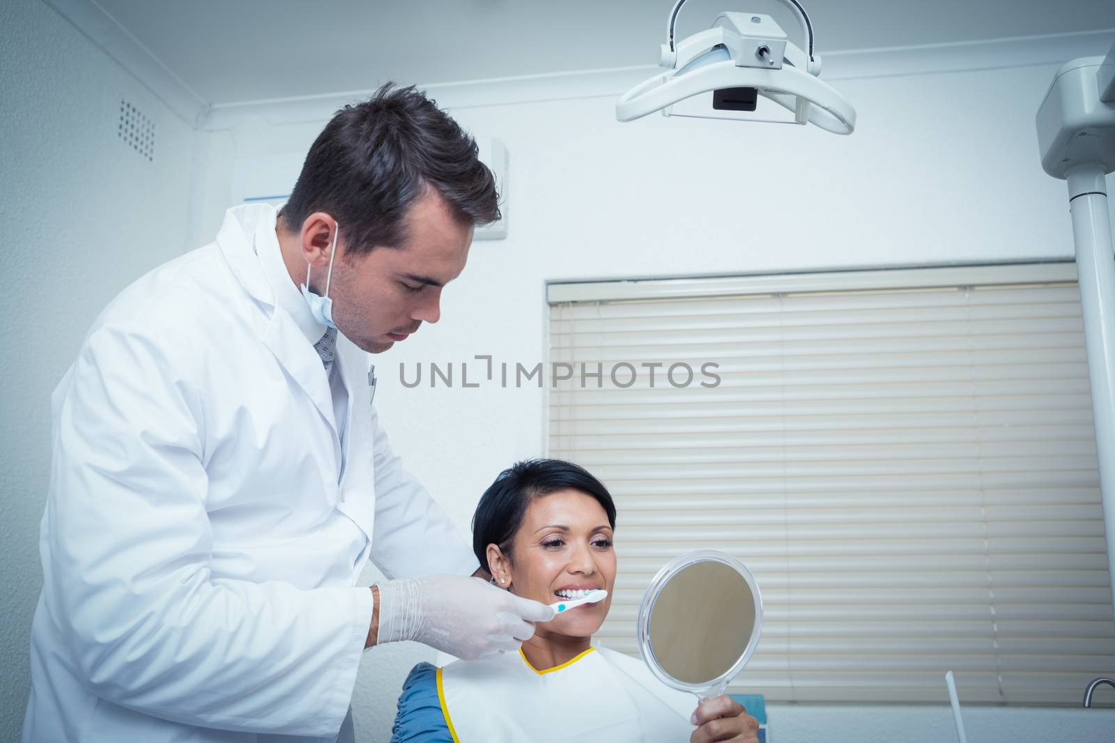 Male dentist brushing womans teeth by Wavebreakmedia