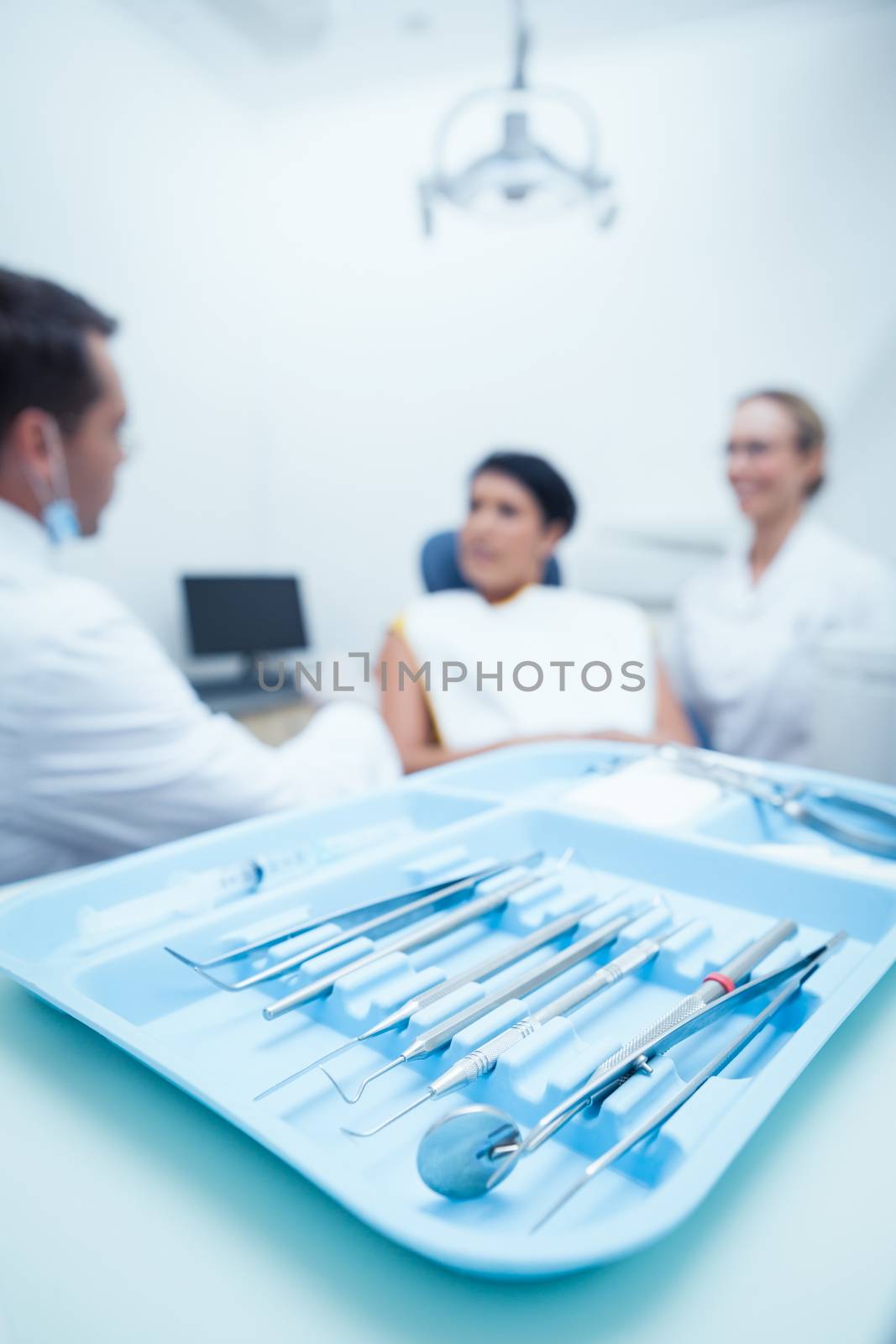 Male dentist and assistant with female patient in the dentists chair
