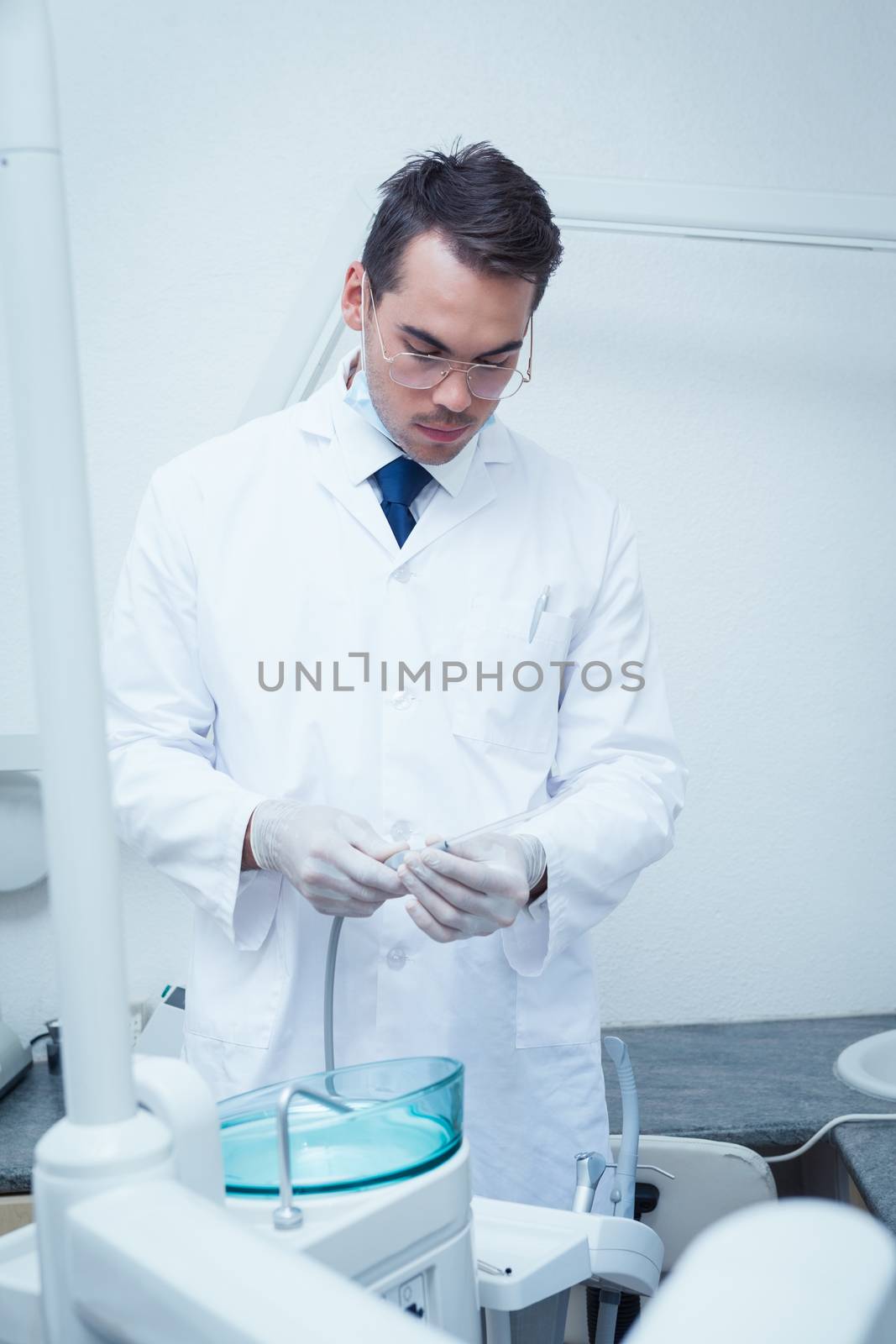 Male dentist holding dental drill by Wavebreakmedia
