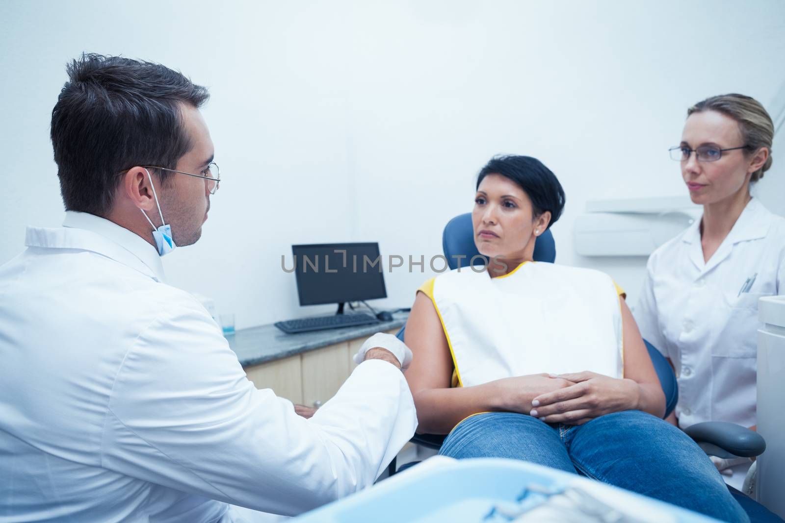 Male dentist and assistant with female patient in the dentists chair