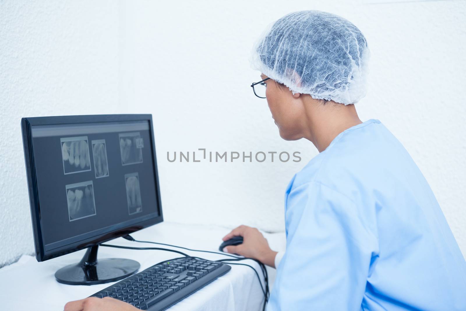 Concentrated female dentist looking at x-ray on computer