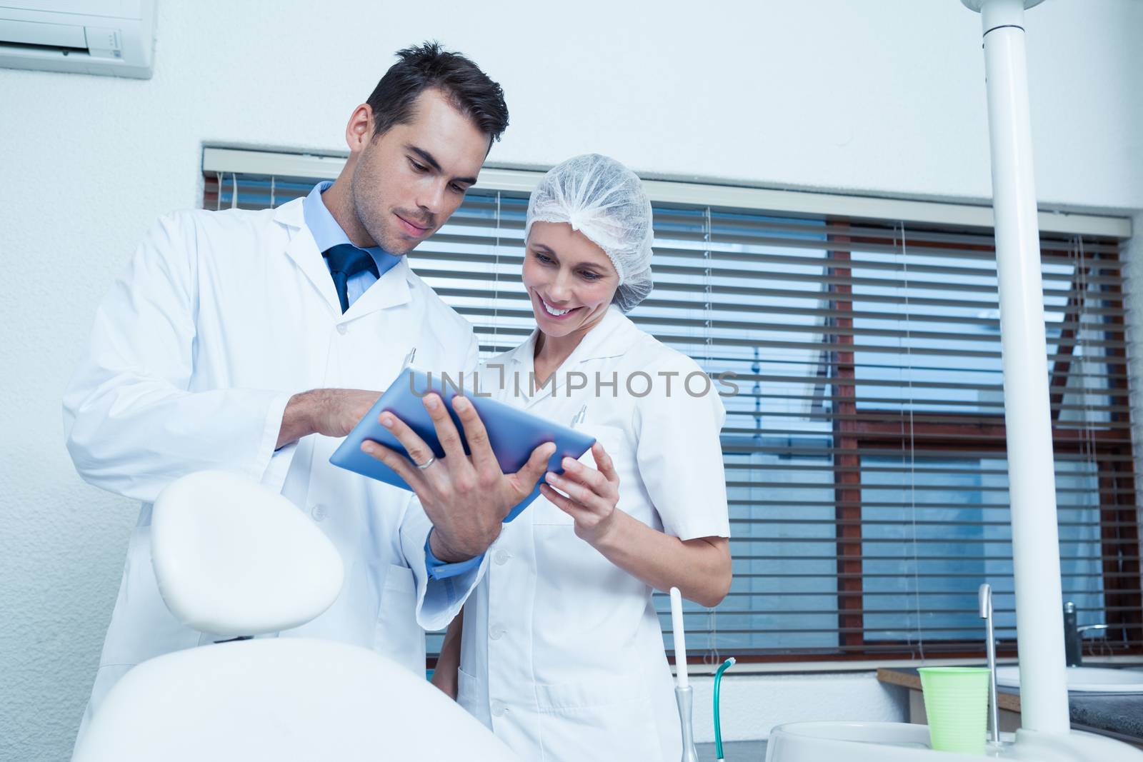 Male and female dentists using digital tablet