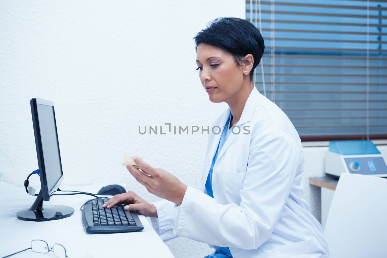 Concentrated female dentist looking at mouth model by computer