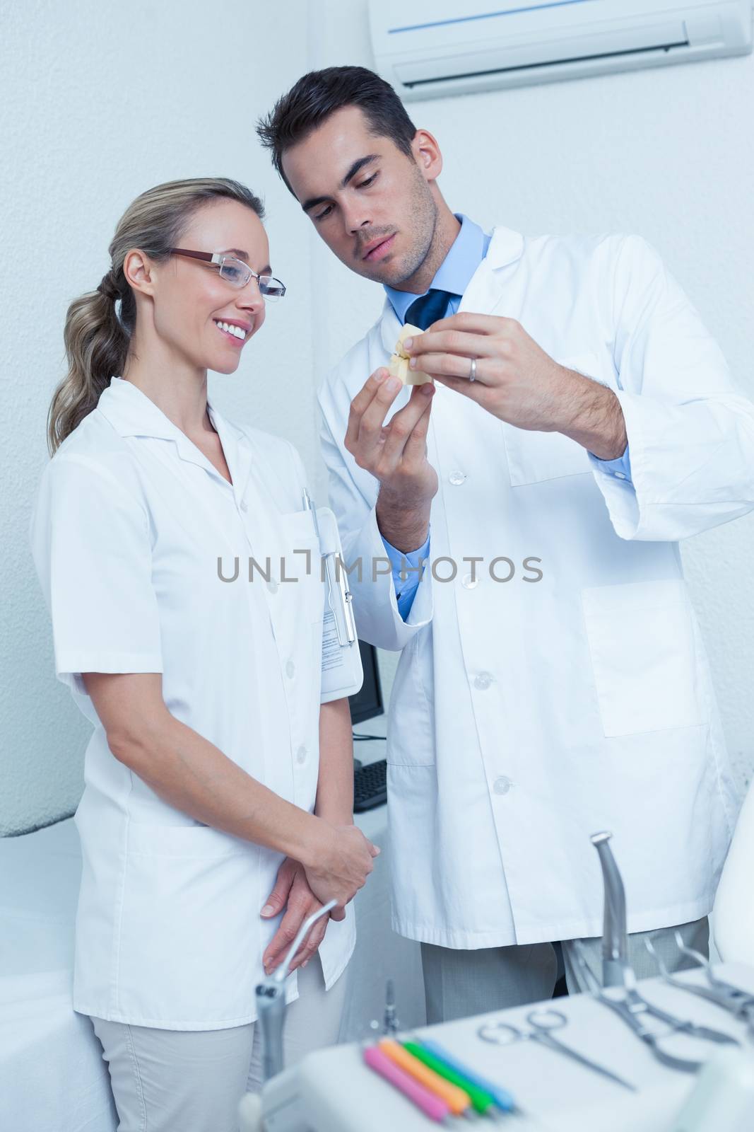 Male dentist and assistant looking at mouth model