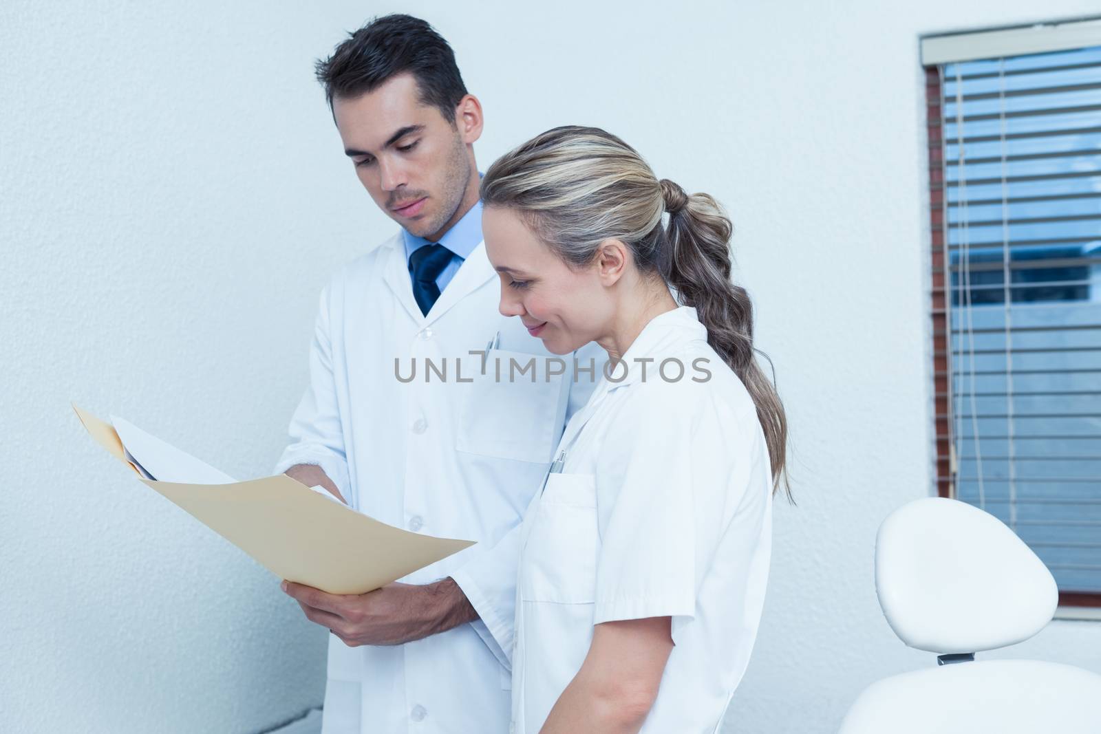 Side view of female and male dentists discussing reports