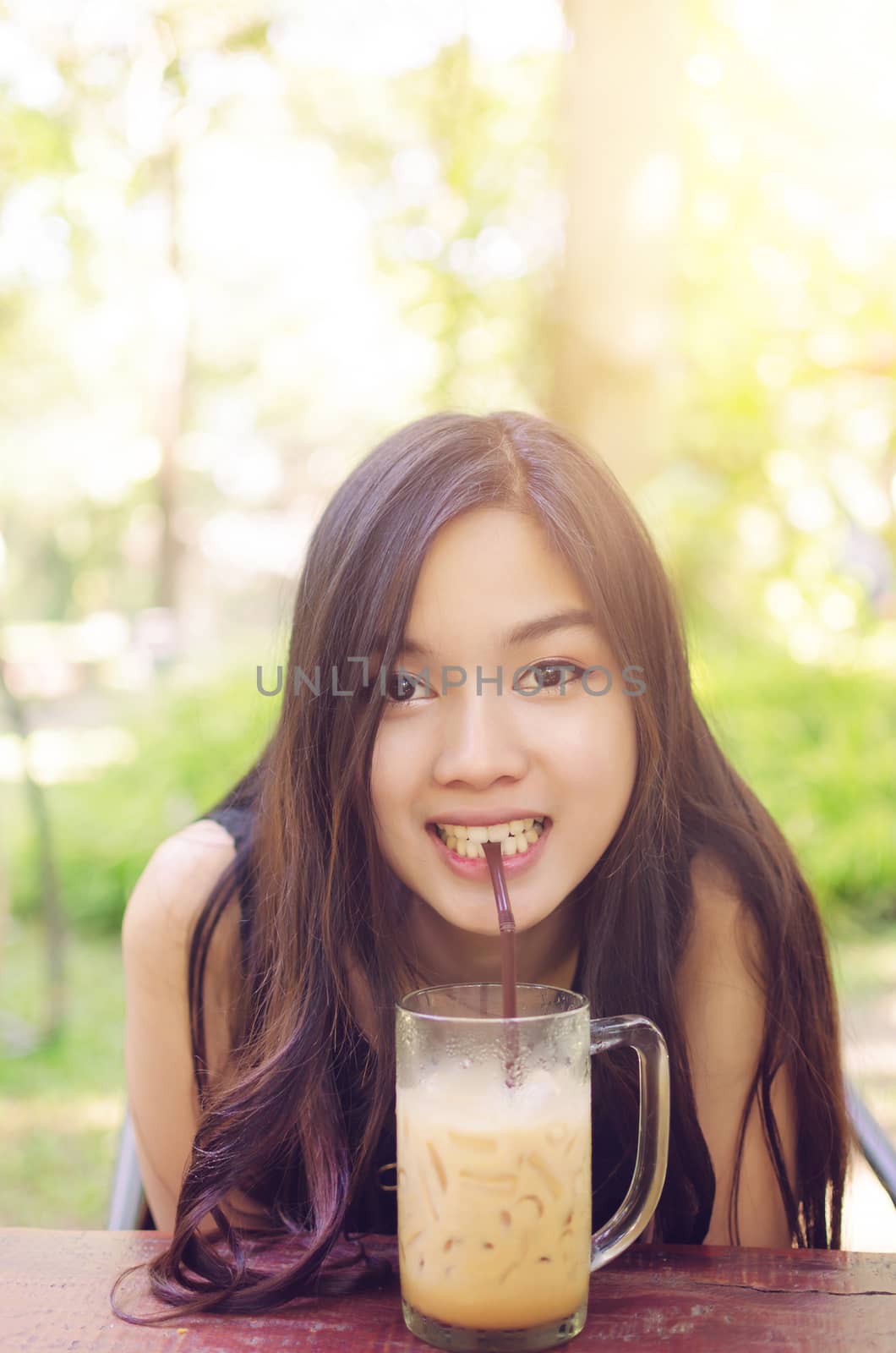 Beautiful asia woman smile and drink coffee. Warm light flare effect on top from the sun.