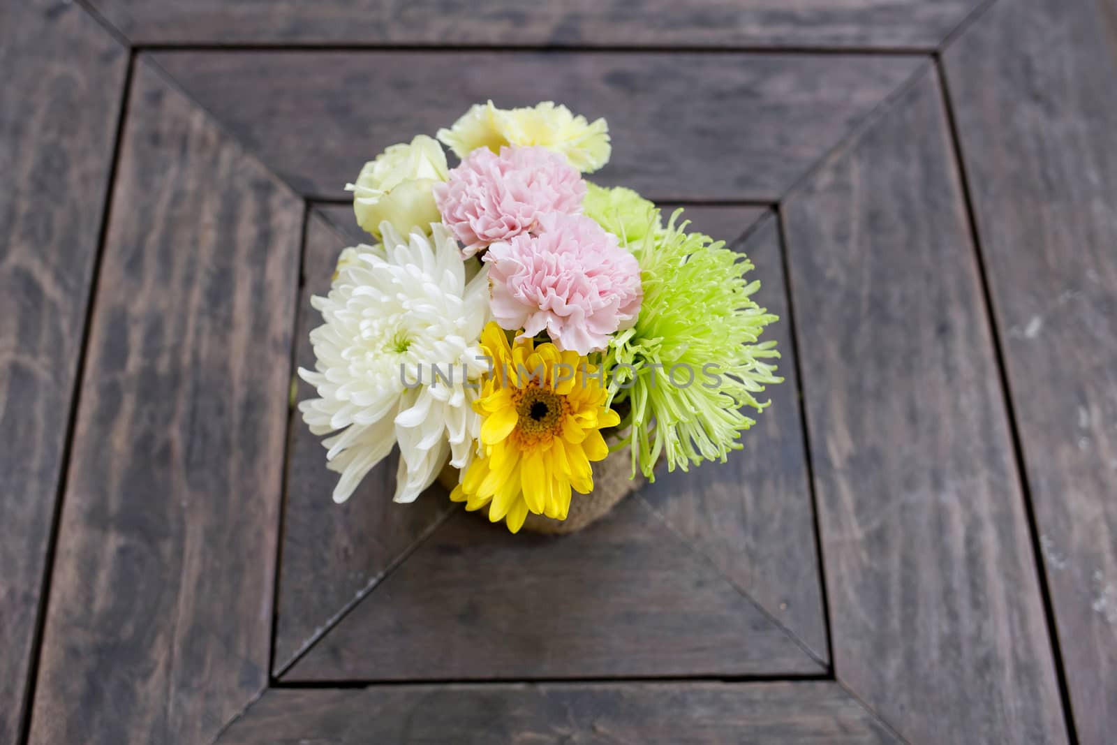 a small bouquet of colorful flowers on a well used old desk or wooden surface.