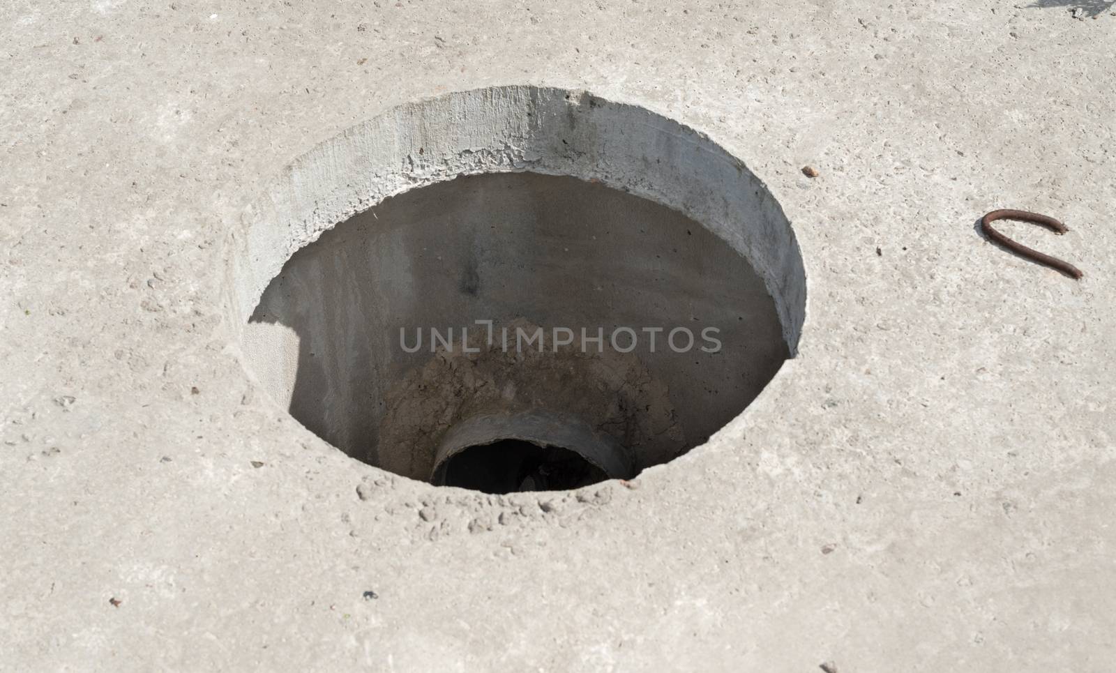 Manhole without cover in new concrete block  by rootstocks
