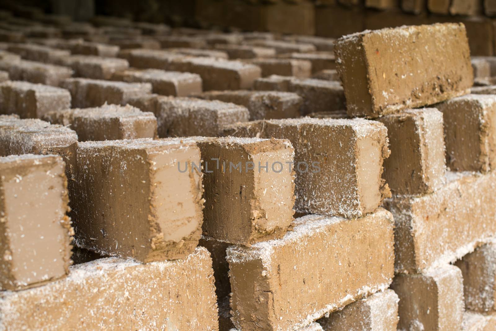 Raw bricks covered with sawdust drying in the open air.