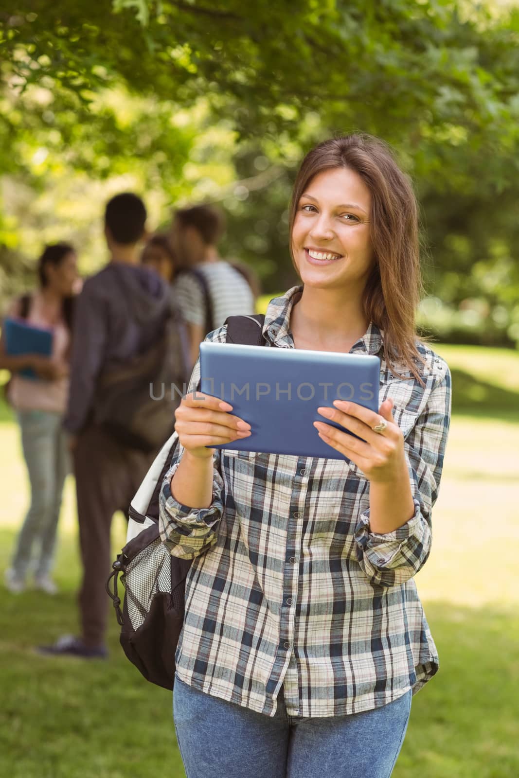 Smiling student with a shoulder bag and using tablet computer by Wavebreakmedia