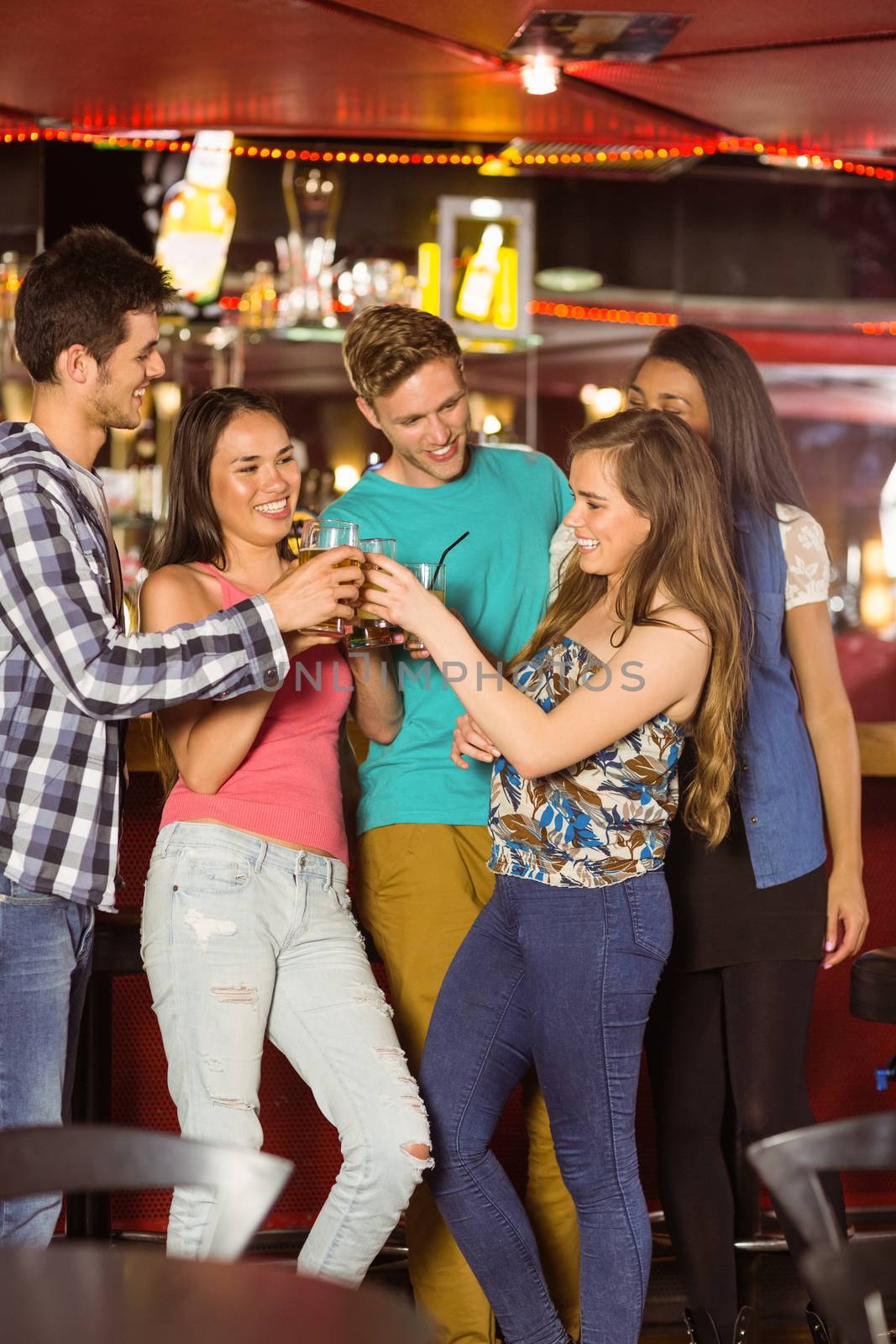 Smiling friends drinking beer and mixed drink in a bar