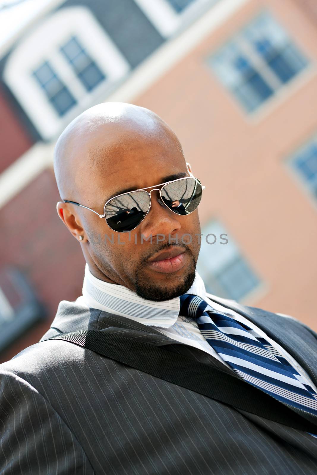 An African American business man wearing his sunglasses and business suit in the city with copy space.
