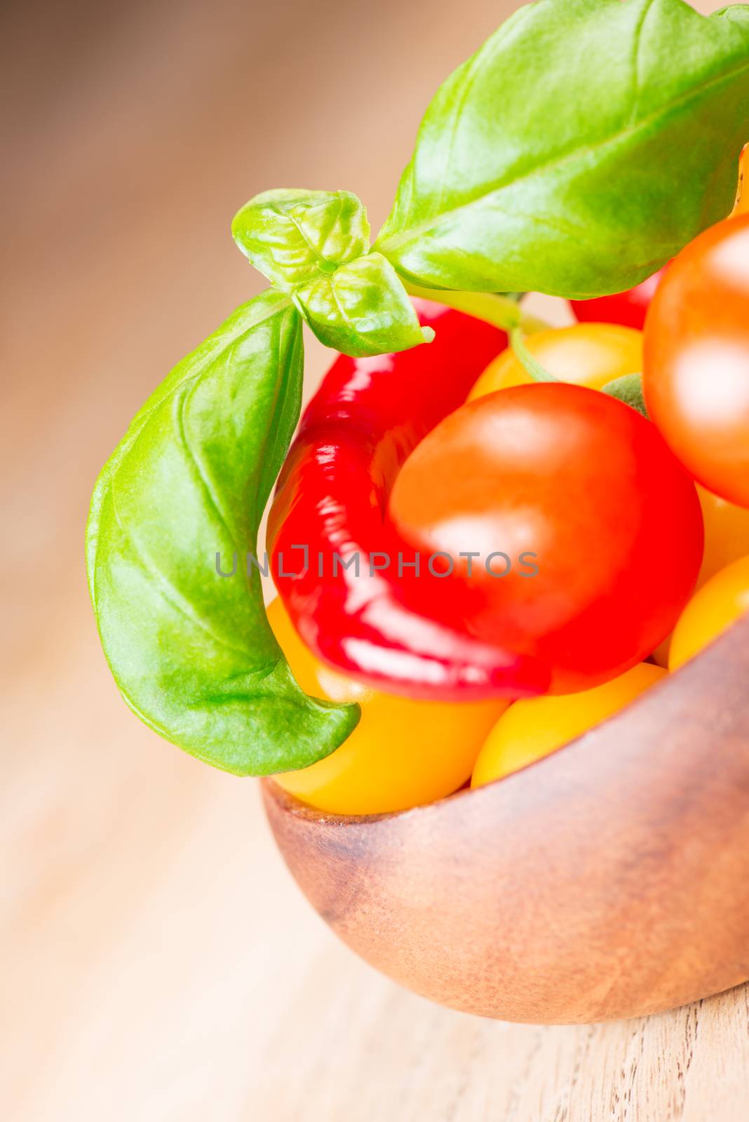 basil leafs with cherry tomatoes and pepper in wooden bowl by Nanisimova
