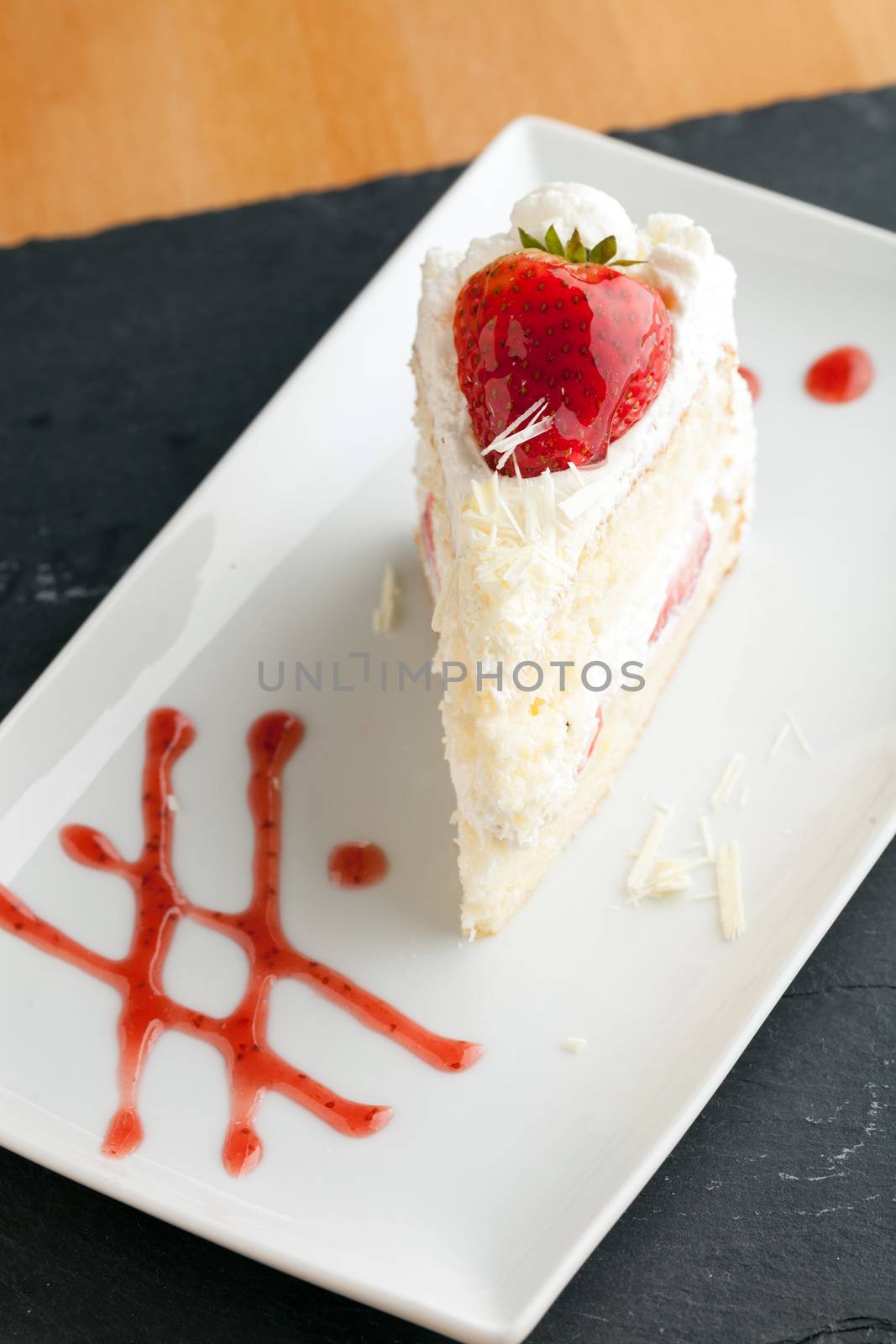 Slice of strawberry shortcake with white chocolate shavings.