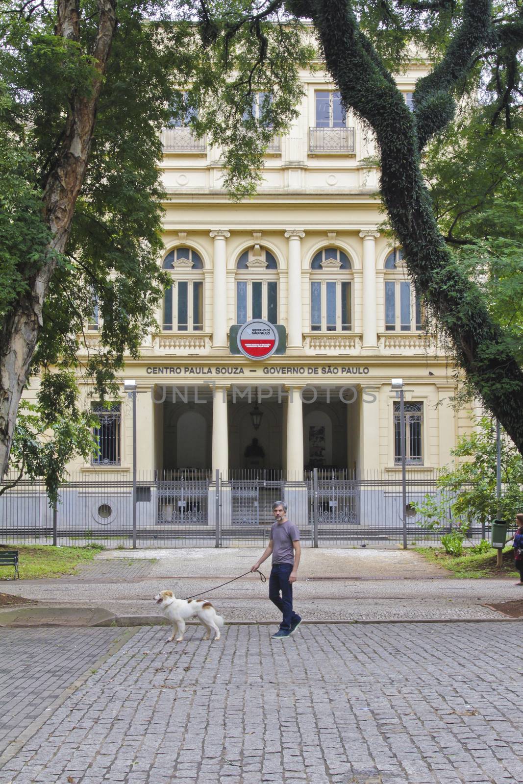 SAO PAULO, BRAZIL - MARCH 8, 2015: An unidentified man walking with a dog in front of Centro Paula Souza University in  Sao Paulo Brazil.