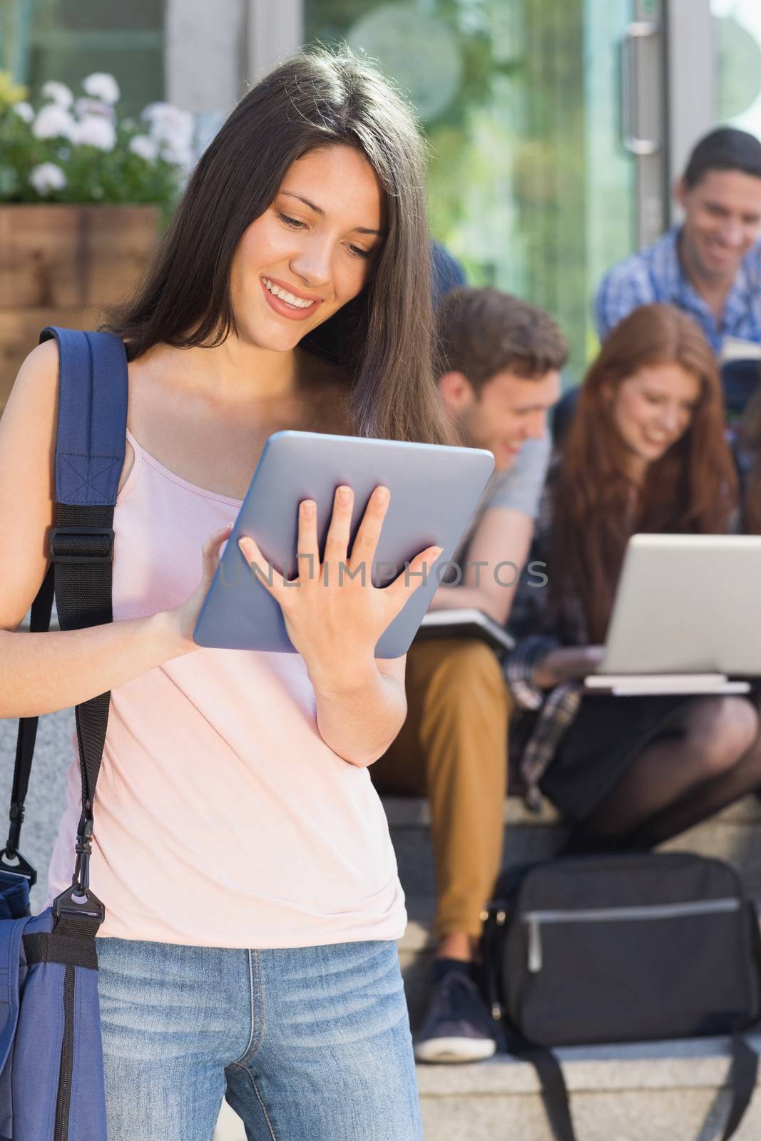 Pretty student using her tablet pc on campus by Wavebreakmedia
