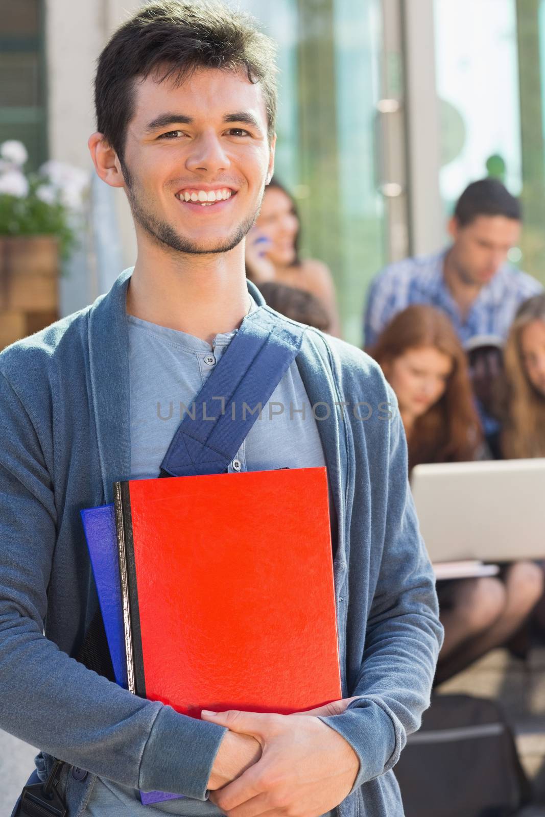 Happy student smiling at camera outside on campus by Wavebreakmedia