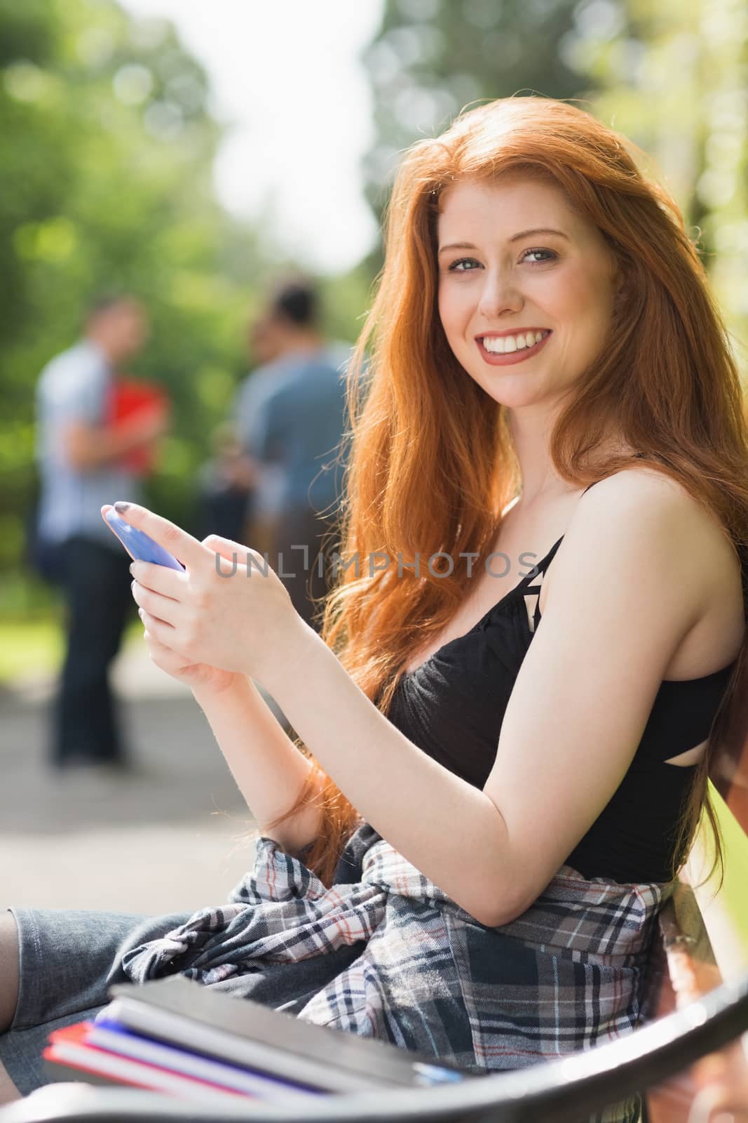 Pretty student sending a text outside at the university