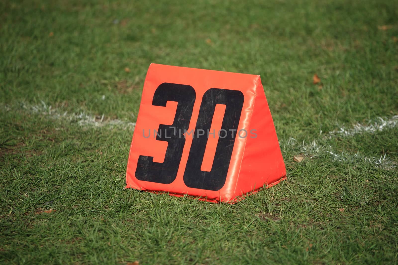 Thirty 30 yard line marker on grass playing football field.