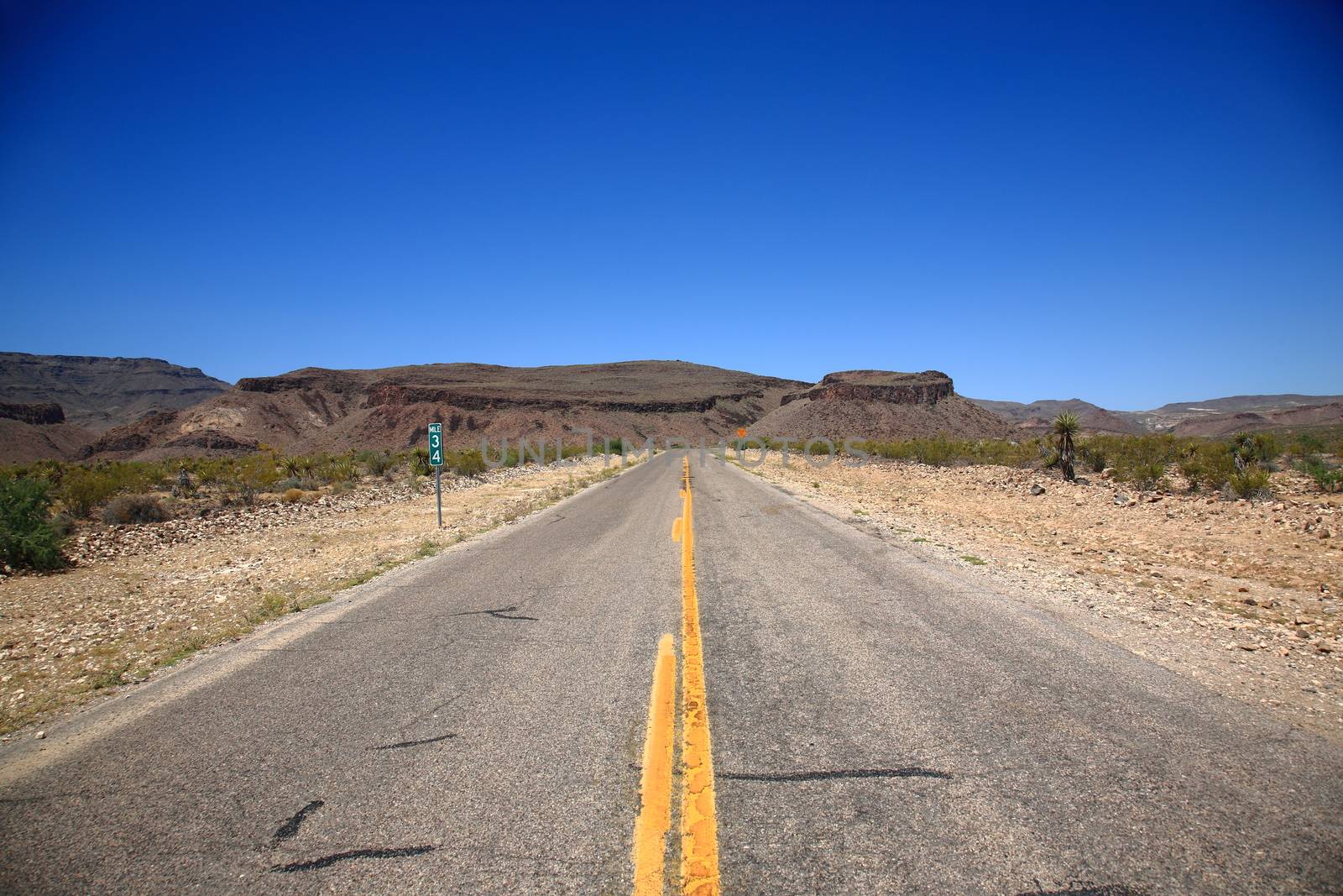 Desert road heads towards the mountains and buttes in Southwestern United States