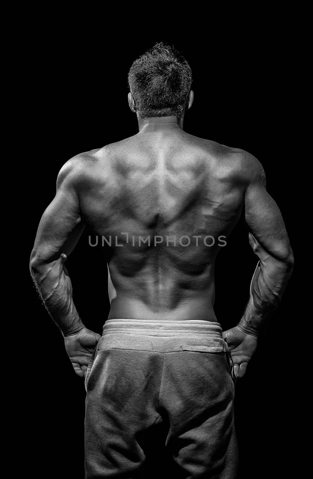 Muscular male model bodybuilder preparing for fitness training, turned back