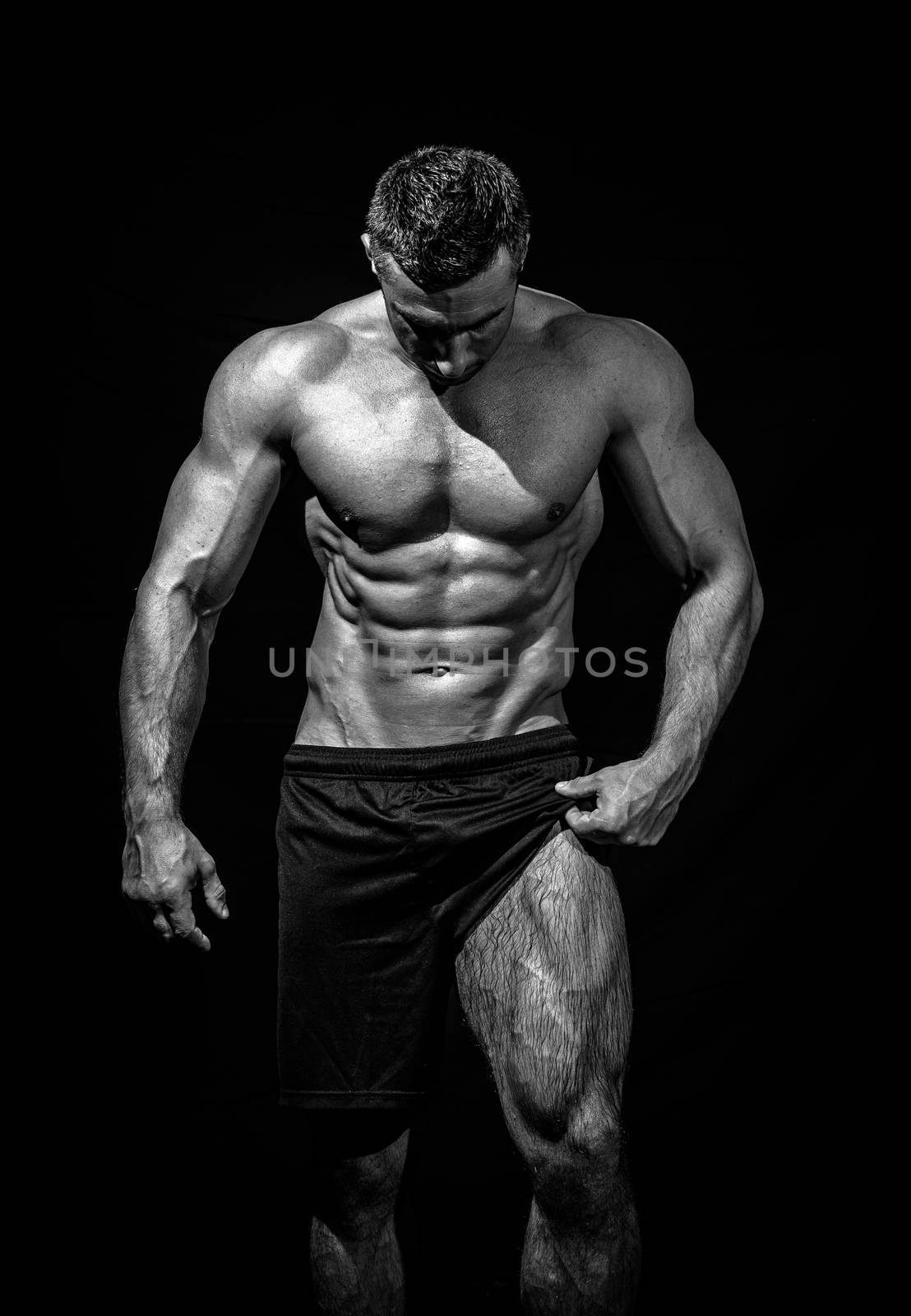 very muscular handsome athletic man on black background, naked torso, black-and-white