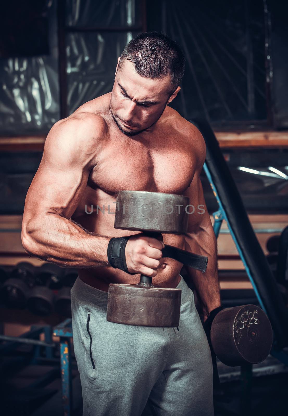 Muscular bodybuilder doing exercises with dumbbells 