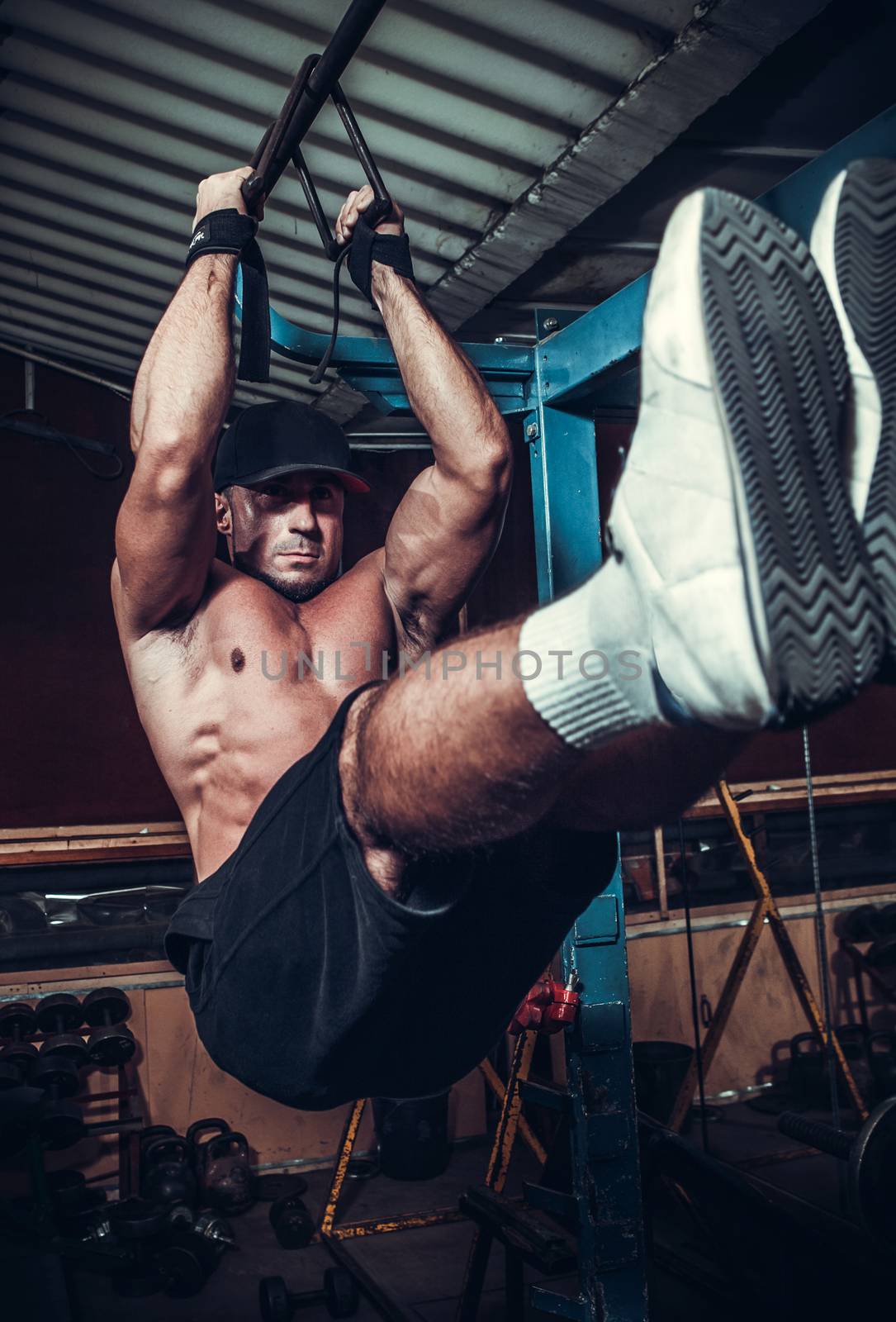 Young Man Performing Hanging Leg Raises Exercise  by Anpet2000