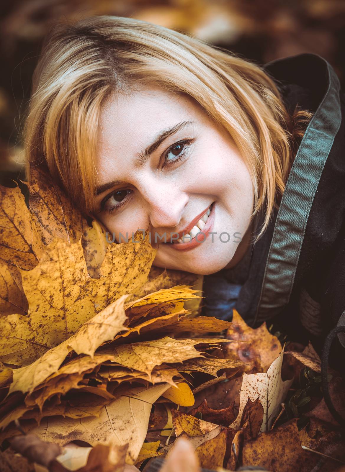 woman with autumn leaves in hand and fall yellow maple garden background