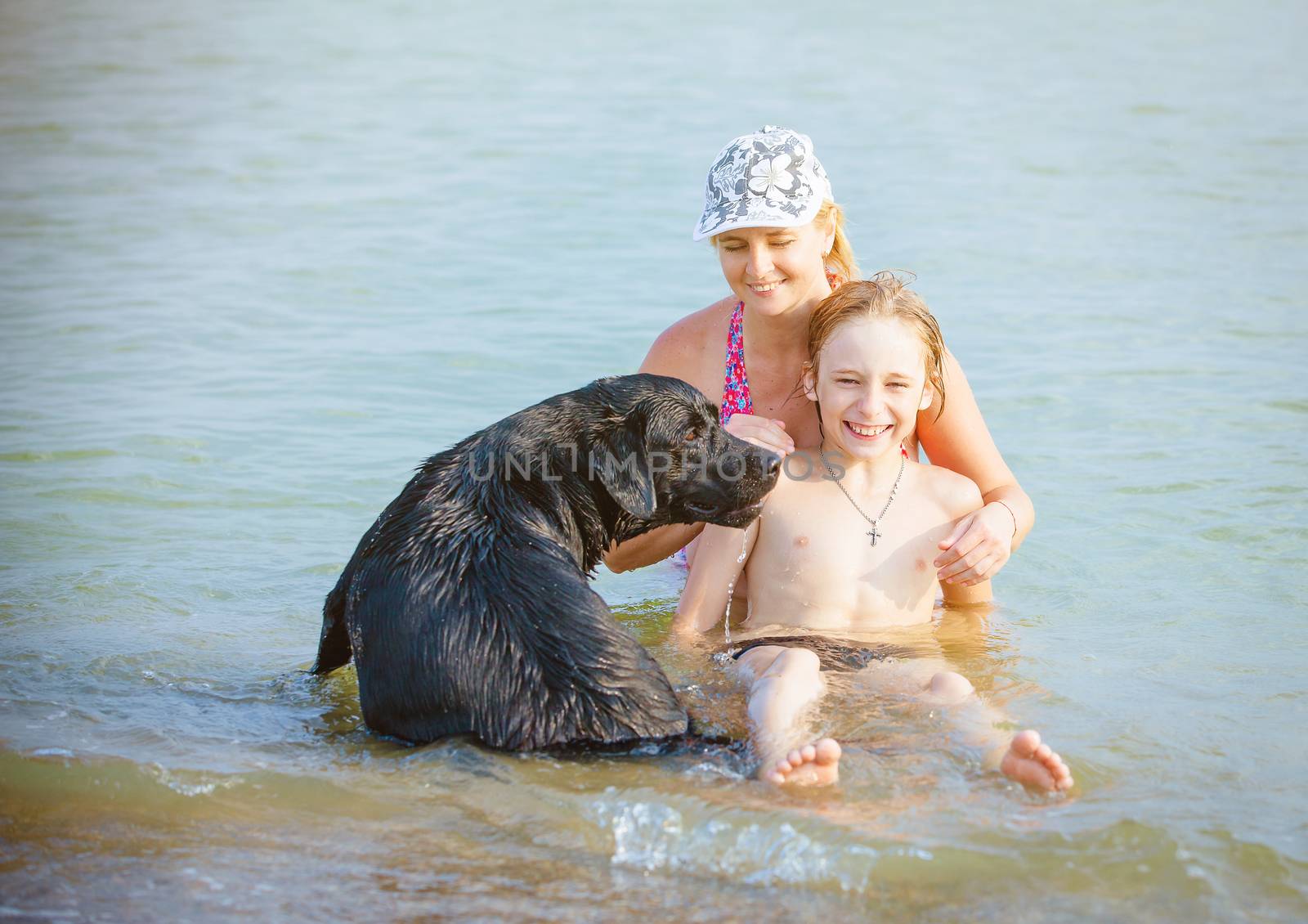 Happy family with dog playing in water