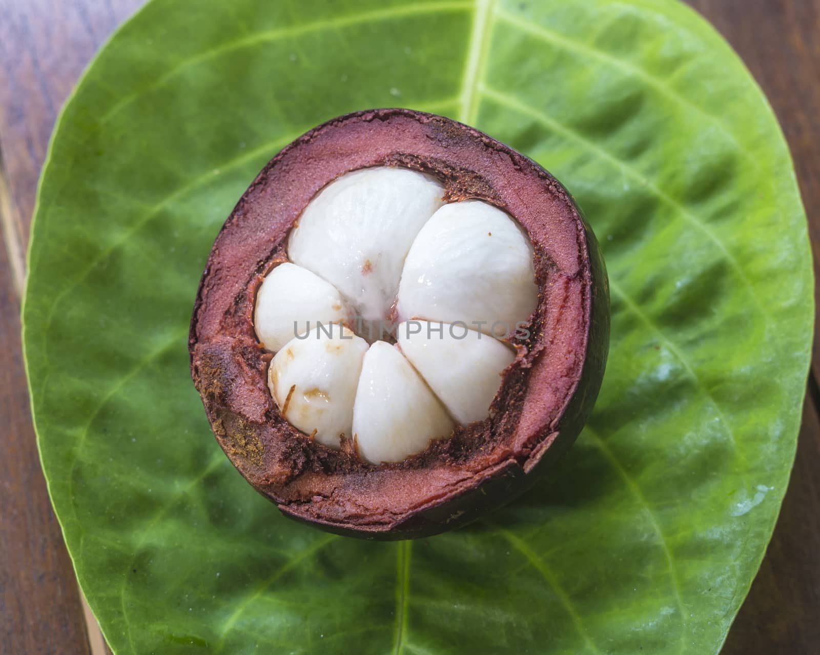 Single Mangostin and Fresh Green Leaf on Wooden Table