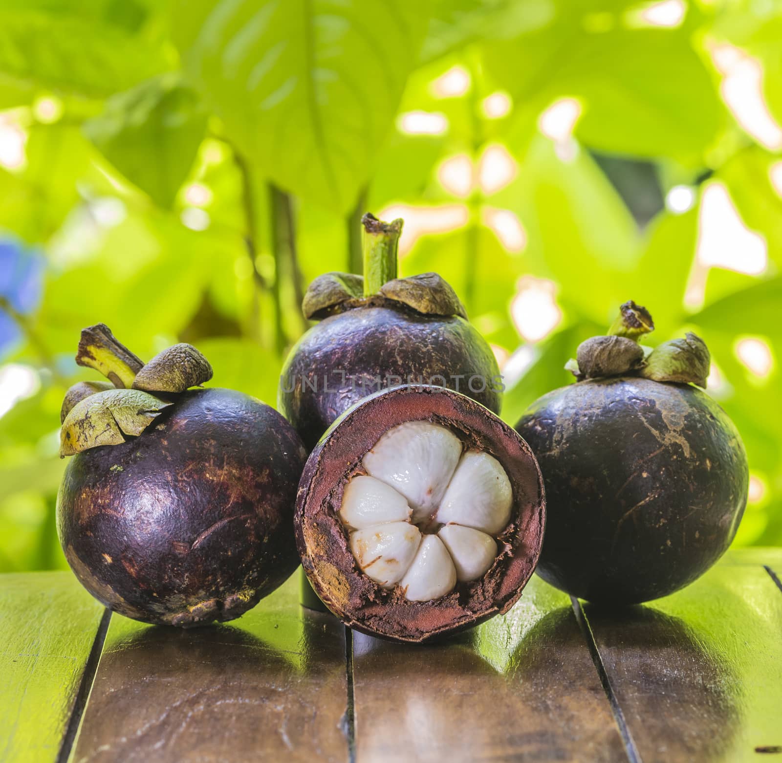 Mangostins and Fresh Green Leaf on Wooden Table