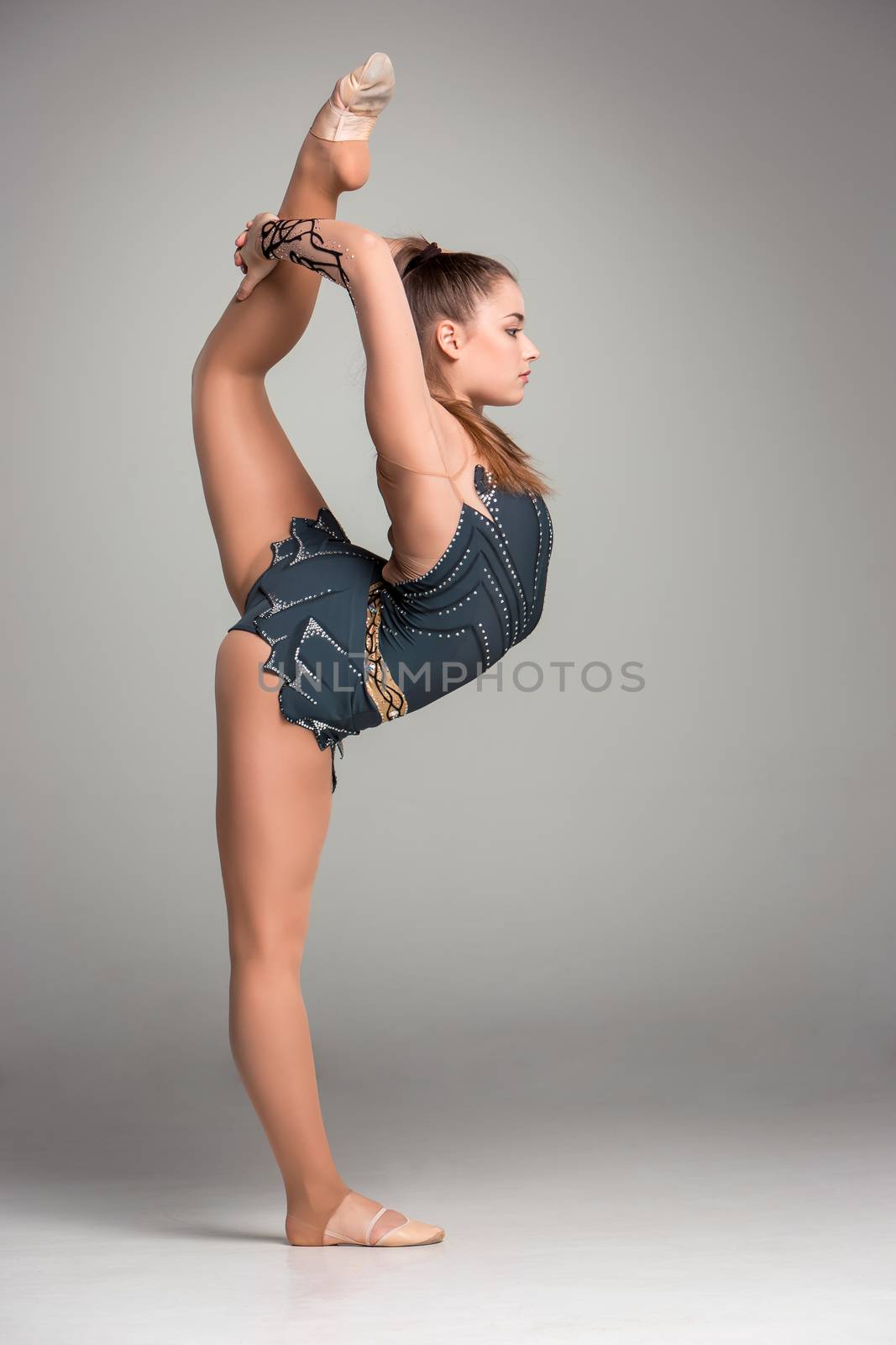 teenager doing gymnastics exercises  on a gray background