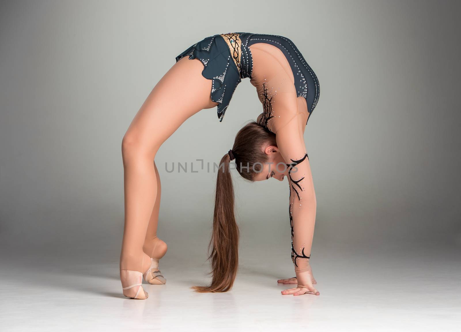 teenager doing gymnastics exercises  on a gray background