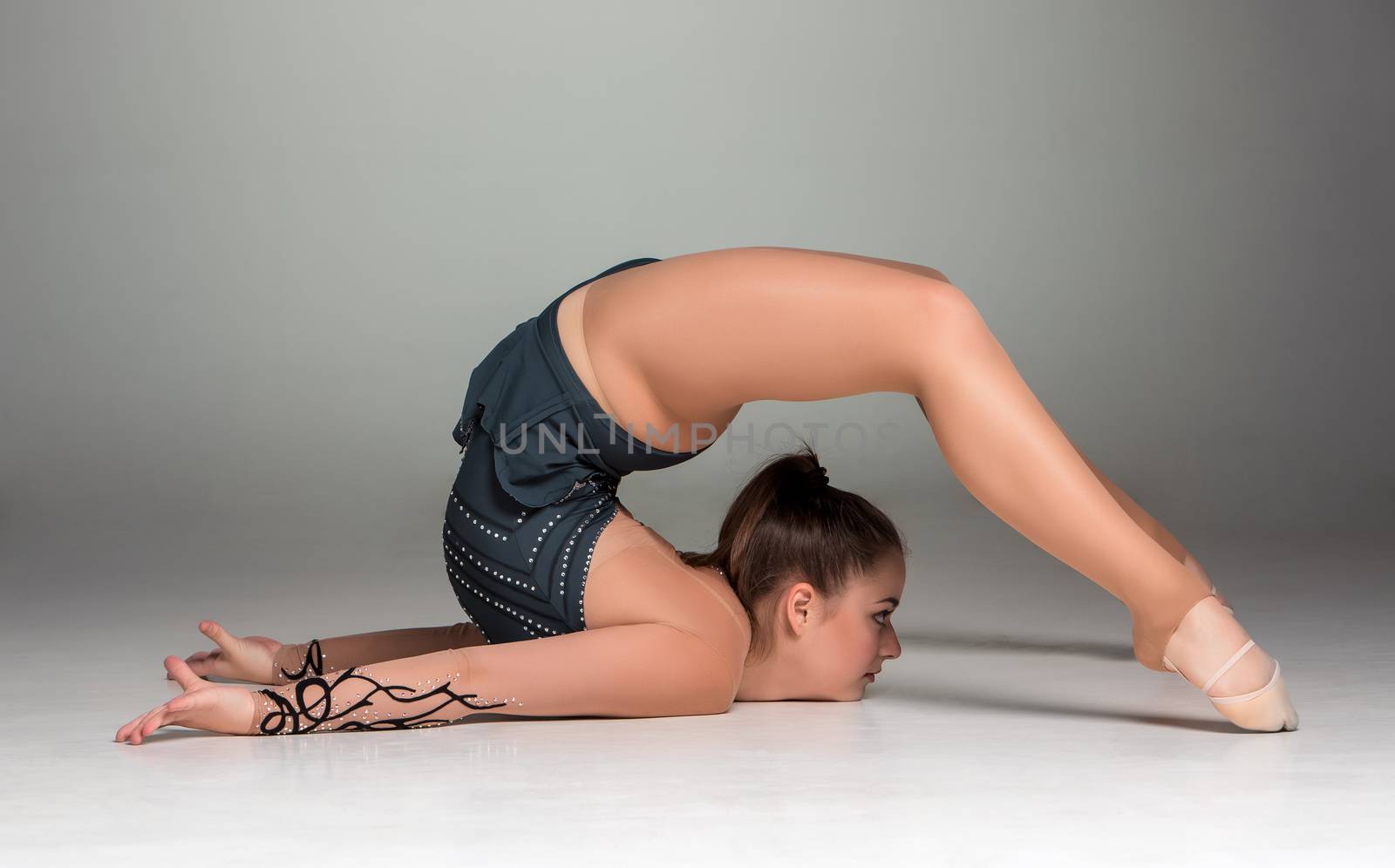 teenager doing gymnastics exercises  on a gray background
