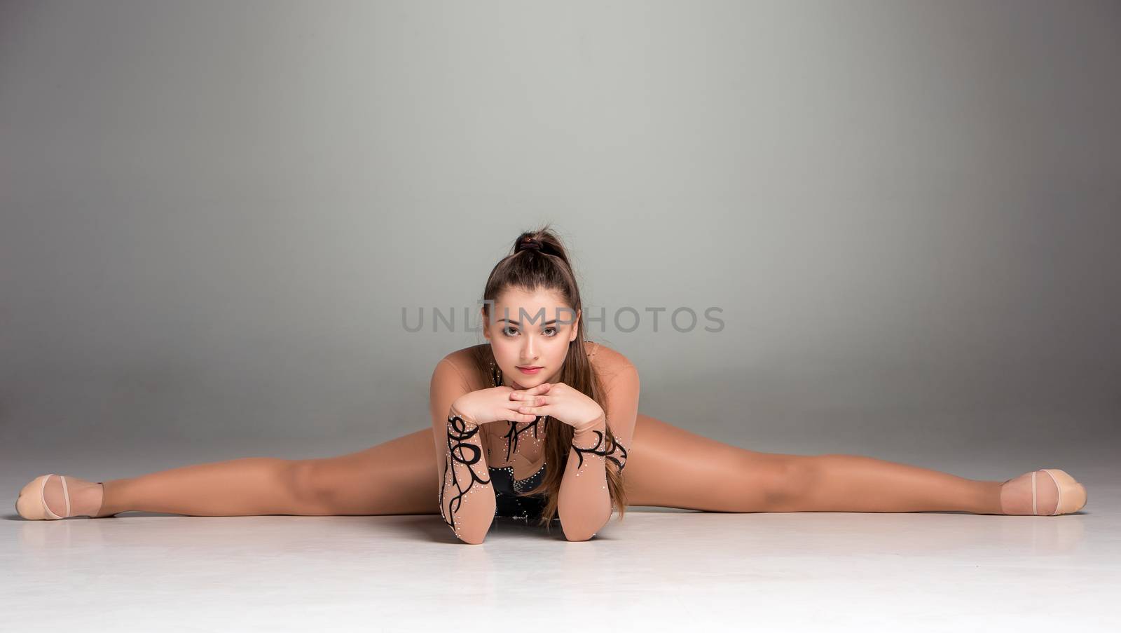 portrait of a gymnast stretching twine on a gray background