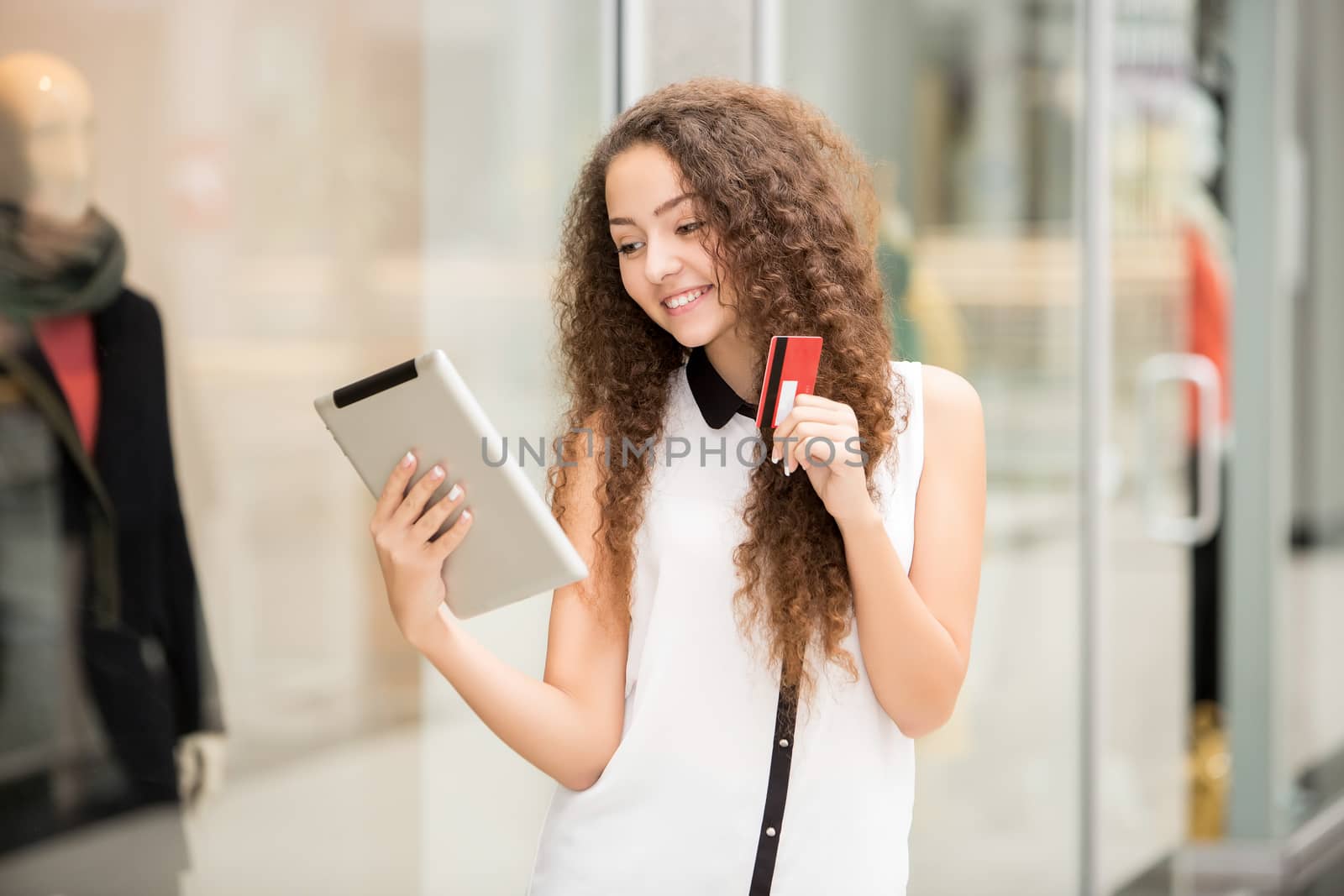 Beautiful young girl paying by credit card for shopping with a laptop against the background of the shopping center