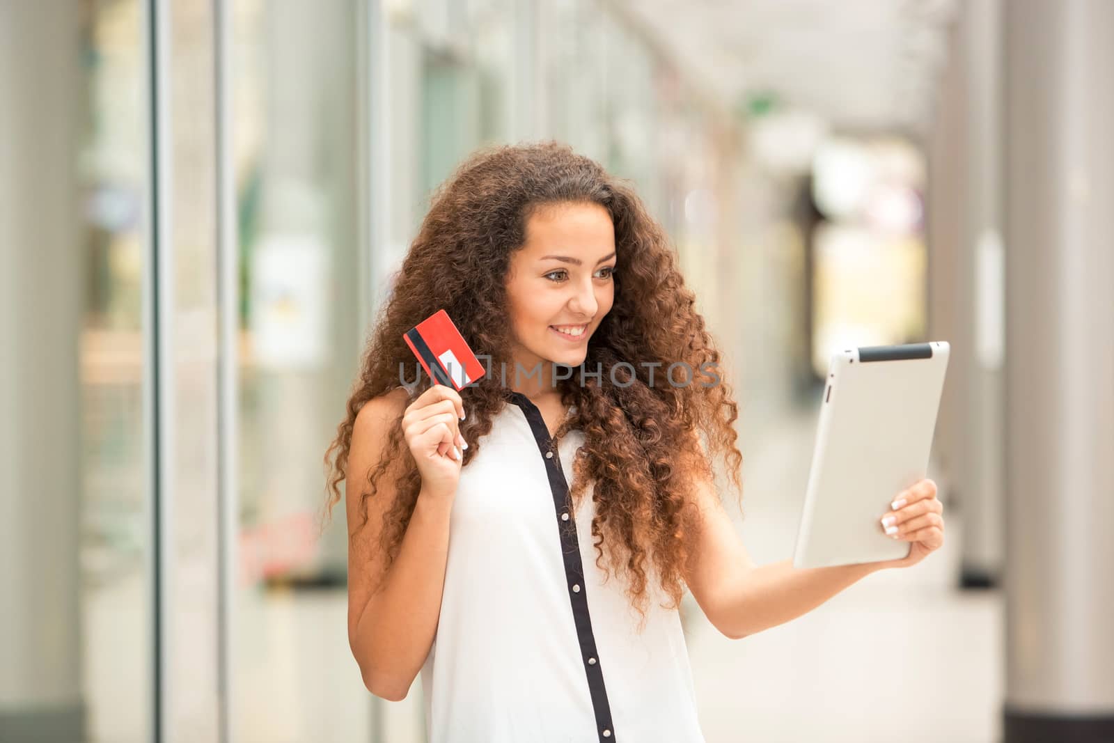 Beautiful young girl paying by credit card for shopping with a laptop against the background of the shopping center