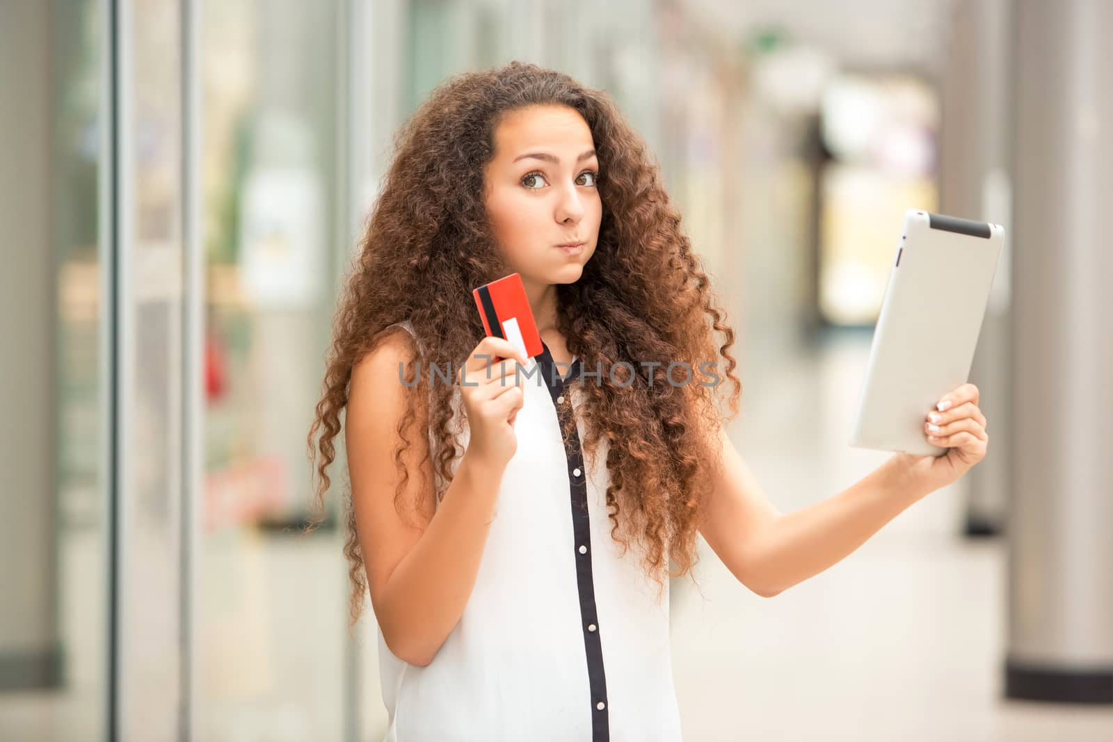 Beautiful young girl paying by credit card for shopping with a laptop against the background of the shopping center