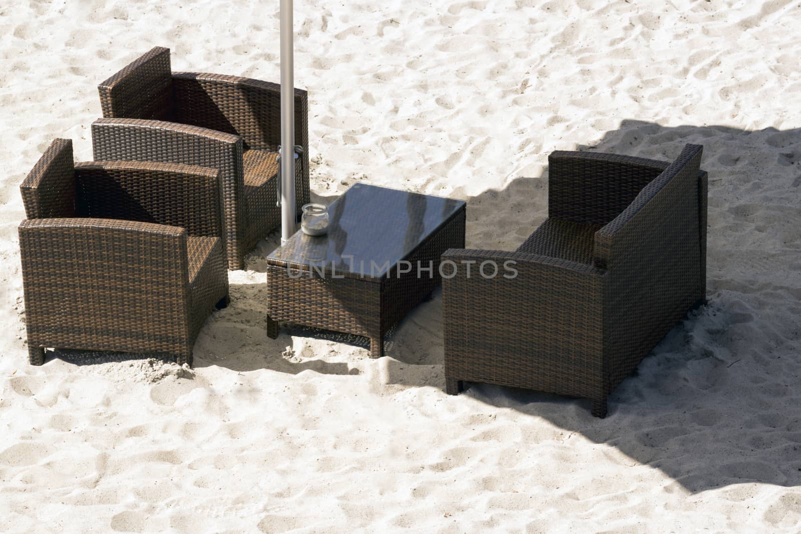 Brown outdoor sofa chairs and table on white sand beach
