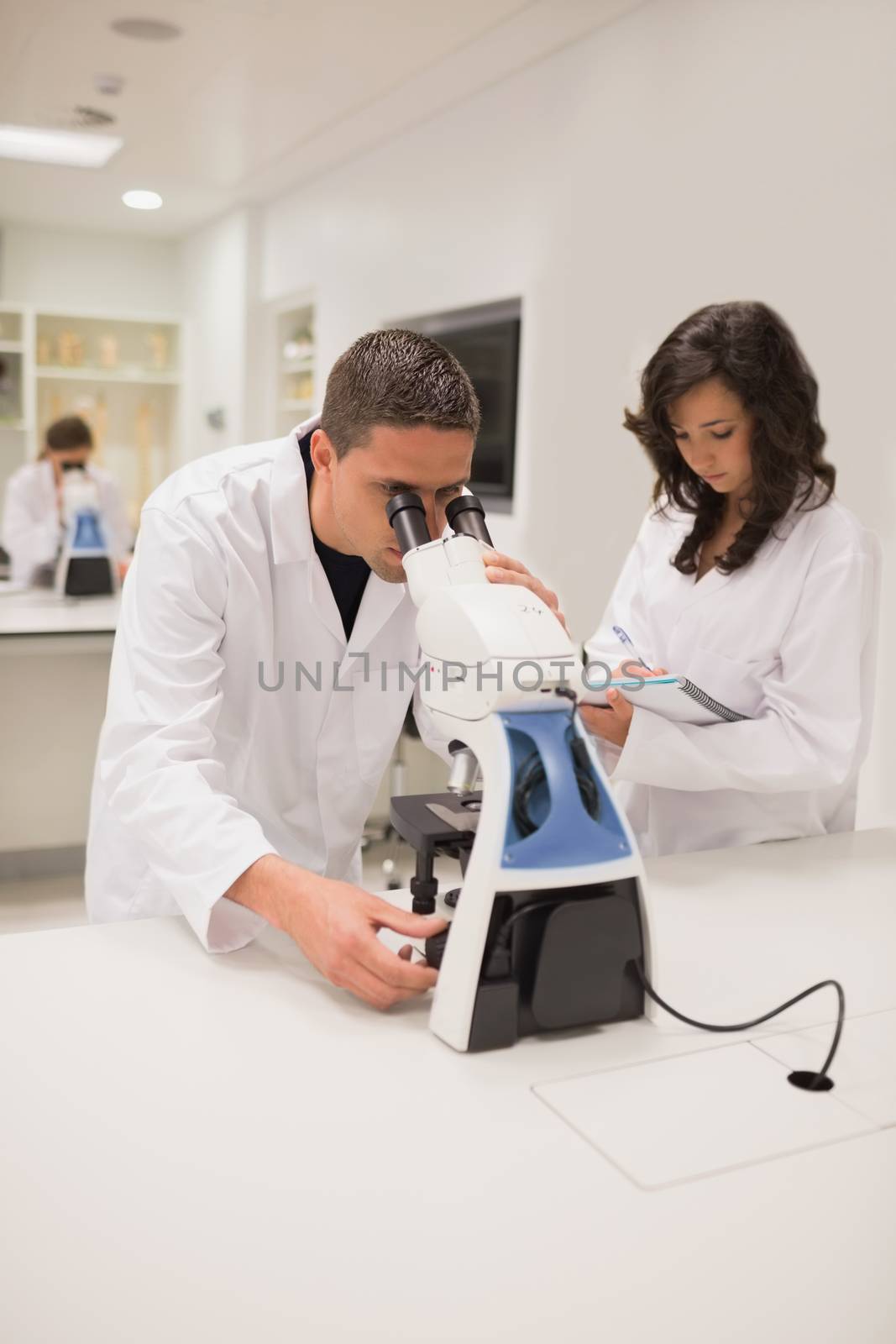 Medical students working with microscope by Wavebreakmedia