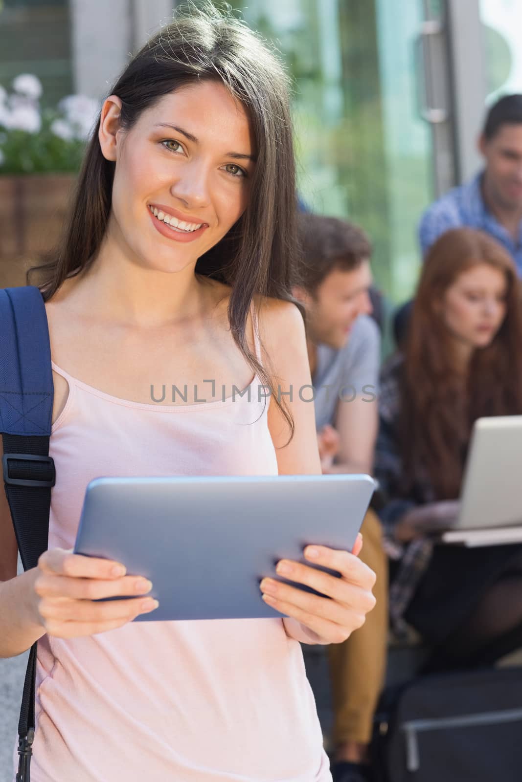 Pretty student using her tablet pc on campus at the university