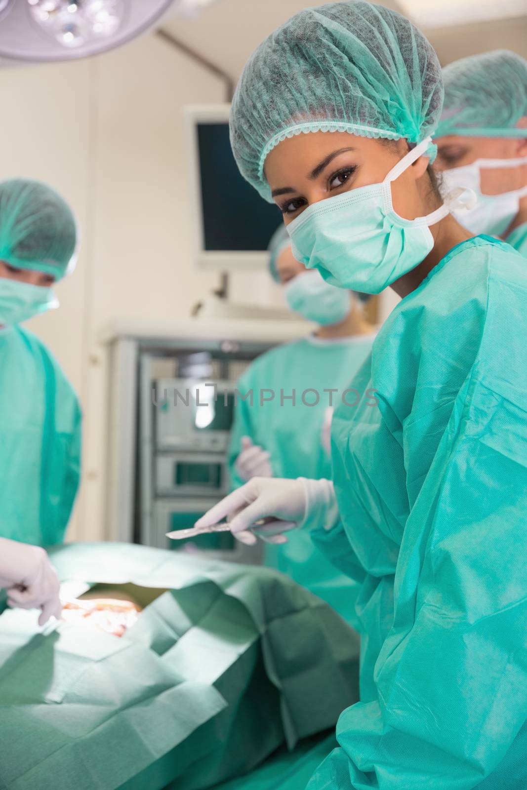 Medical student looking at camera during practice surgery by Wavebreakmedia