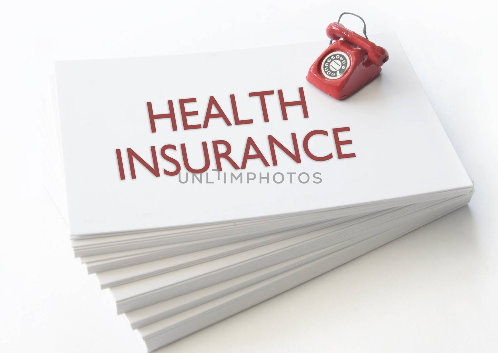 Small telephone on top of a stack of business cards with health insurance 
