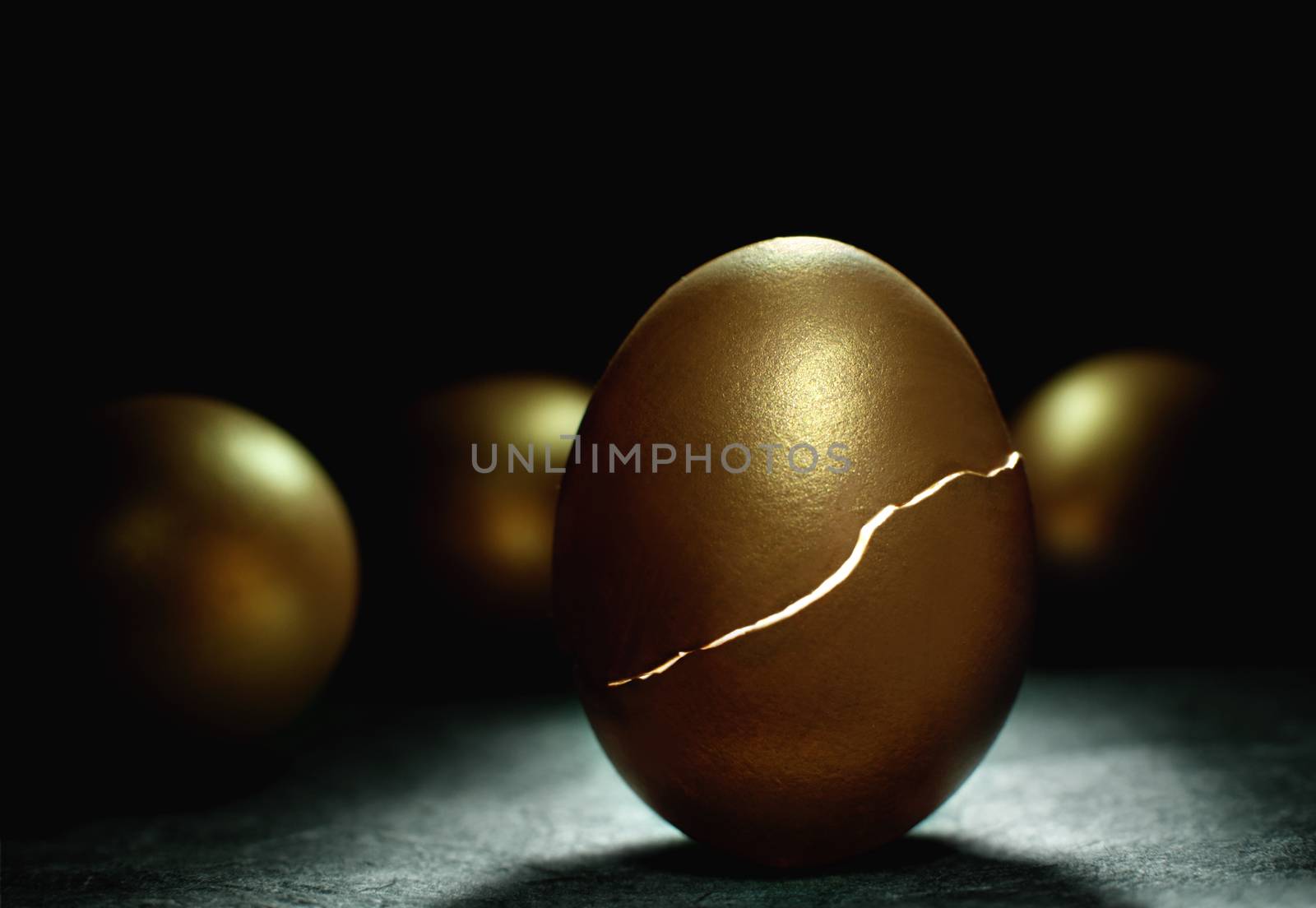 Gold nest egg hatching with light inside symbolising investments such as retirement and savings 