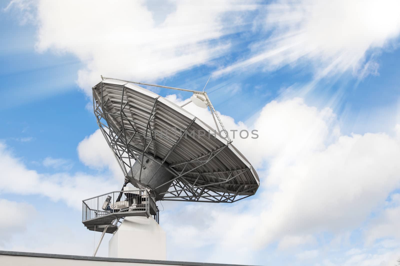 Telecommunications radar parabolic radio antenna as part of global communication technology stations system against sunny sky with sun rays sunbeams. Toned and filtered stock photo.