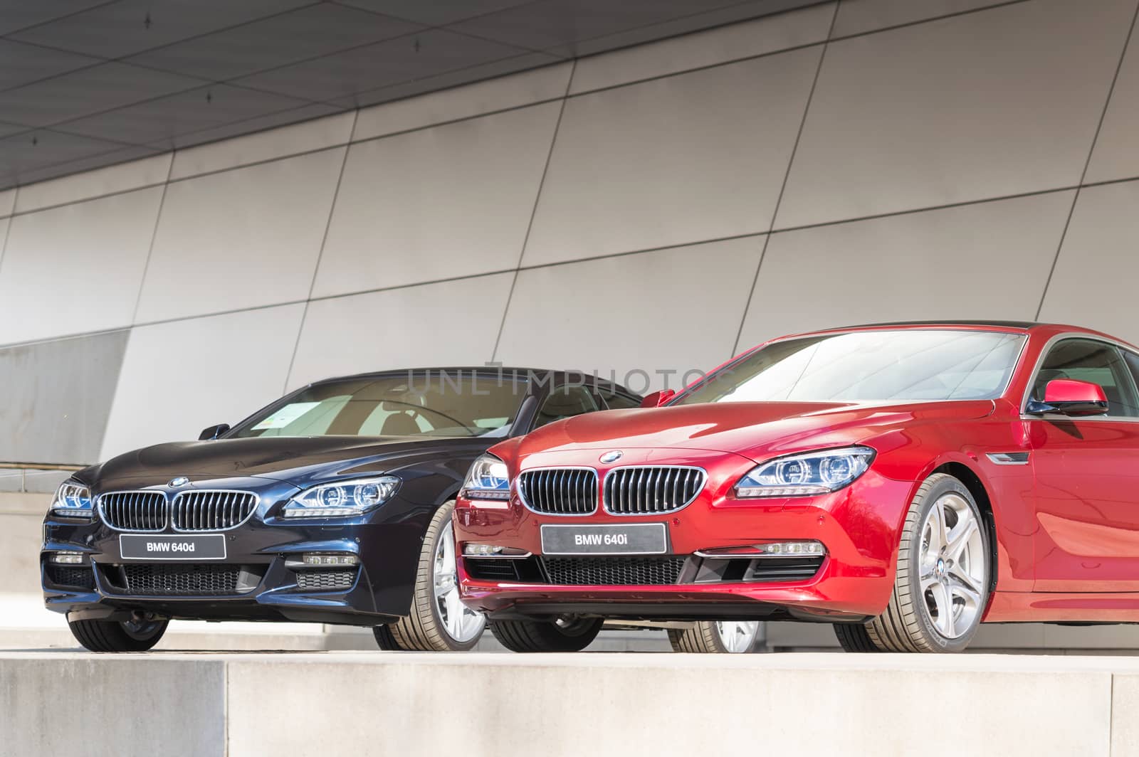 MUNICH, GERMANY - APRIL 12, 2015: New modern BMW 640 model lineup of first class exclusive business sedan cars. Front view of dark blue 640d and red 640i.
