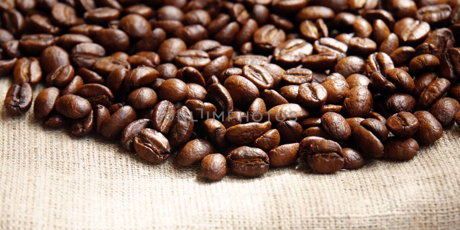 Background from coffee beans on fabric closeup by Chiffanna
